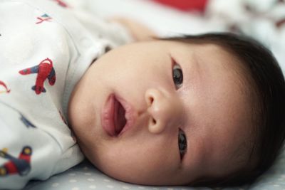 Close-up portrait of baby girl on bed