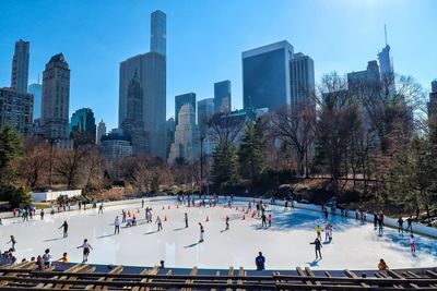 High angle view of people ice-skating against modern buildings in city