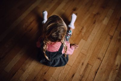 Rear view of girl sitting on hardwood floor