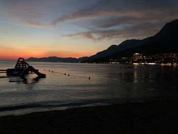 Silhouette boats on beach against sky during sunset