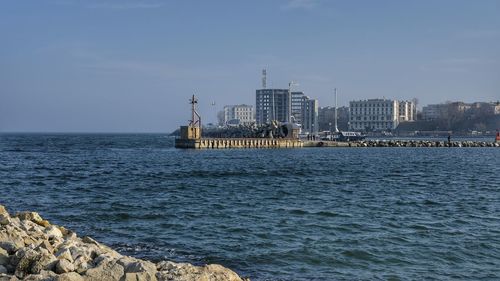 Scenic view of sea by buildings against sky