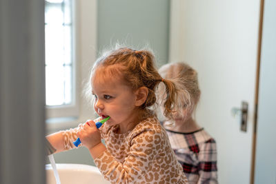 Cute girl brushing teeth at home