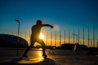 Low angle view of silhouette woman standing against clear sky during sunset