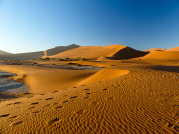 Scenic view of desert against clear blue sky