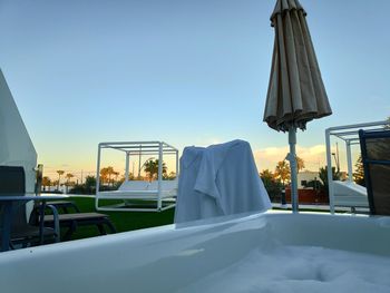 Lounge chairs by swimming pool against clear sky