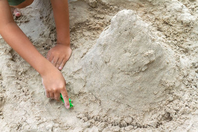 Low section of woman playing on sand