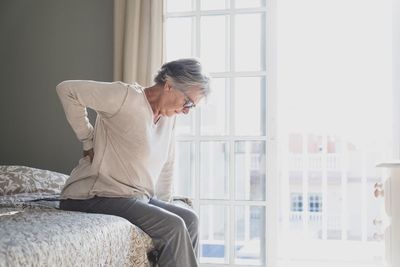 Side view of senior woman resting on bed at home