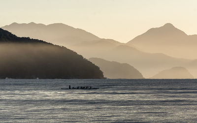 Scenic view of sea and mountains against sky during sunset