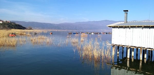 Wooden posts in lake against sky