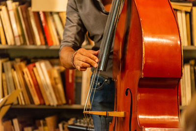 Midsection of man holding musical instrument in library