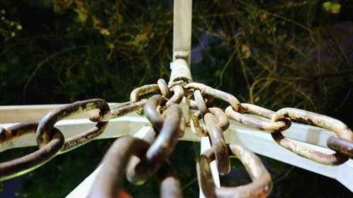 Close-up of chane tied to metal fence