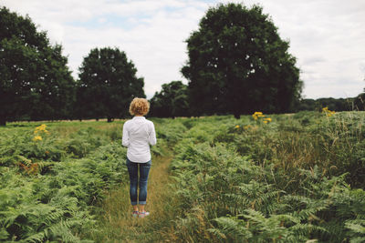 Rear view of young woman standing on grassy field