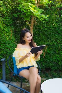 Young woman looking away while sitting on mobile phone