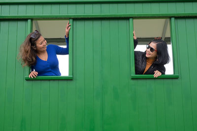 Smiling friends looking through window of shed