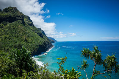 Scenic view of green mountains and sea against blue sky