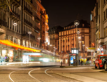 Illuminated street amidst buildings in city at night