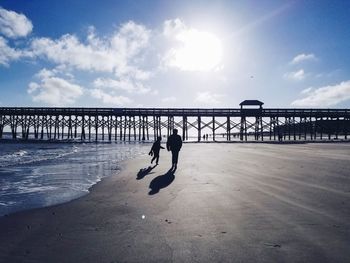 Silhouette boys on beach against sky