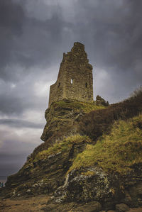 Rock formations on mountain against sky, castle looking over shore 