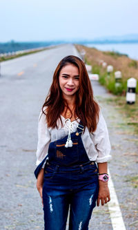 Portrait of smiling young woman standing on road