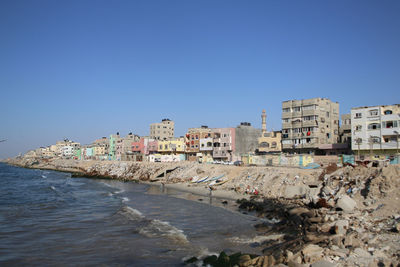 View of city by sea against clear blue sky