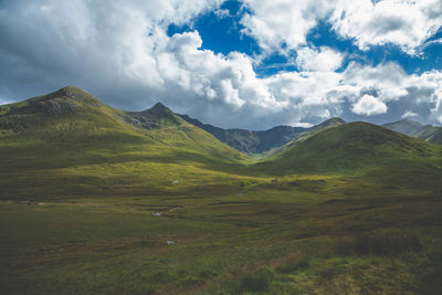 Scenic view of green landscape and mountains against sky