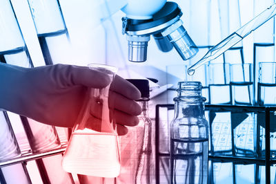 Cropped hand of scientist holding chemical in flask at laboratory