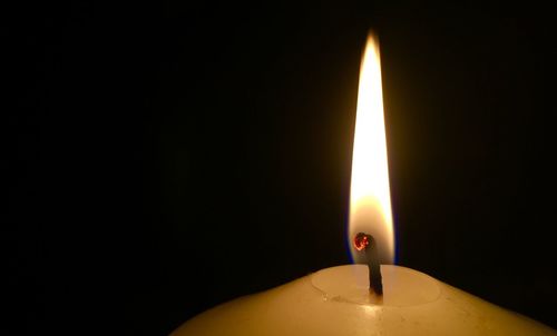 Close-up of lit candle in darkroom