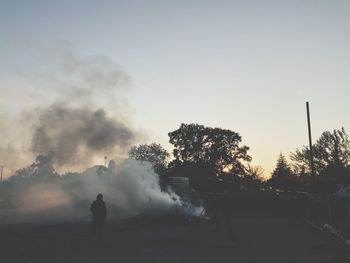 Rear view of silhouette man standing by tree against sky