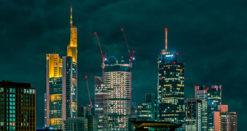 Illuminated buildings in city against sky at night