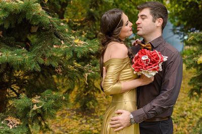 Young couple standing against plants