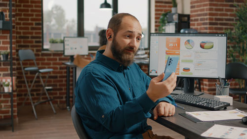 Portrait of man using laptop at office