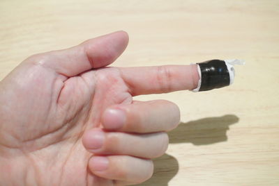 High angle view of hand with wounded finger on wooden table