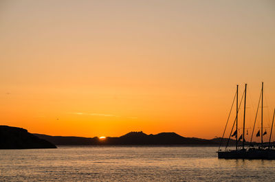 Silhouette sailboats in sea against sky during sunset