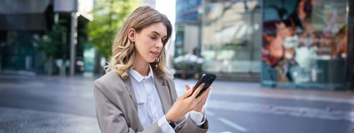 Young woman using mobile phone in city