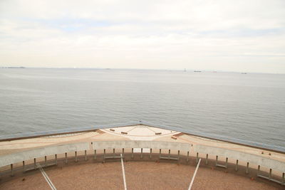 Pier on sea against cloudy sky