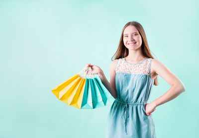 Portrait of smiling woman standing against blue background