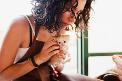 Midsection of woman holding kitten at home