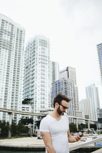 Young man against buildings in city against sky