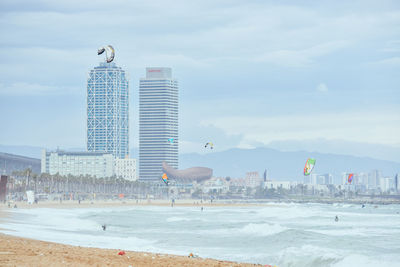 Seagull flying over beach against sky in city