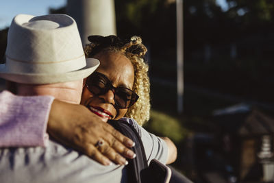 Senior woman embracing man on sunny day