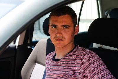 Happy smiling caucasian young man sitting in car. 20s guy looking from open window. silver grey 