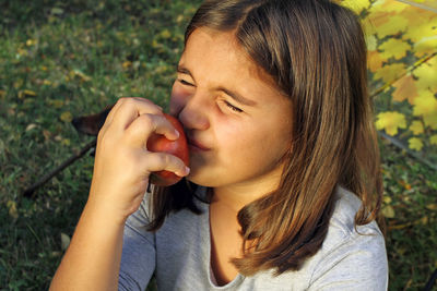 Girl holding fruit while sitting on field