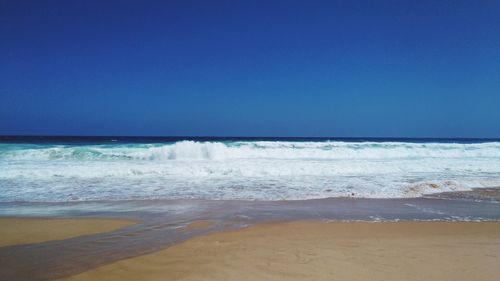 Scenic view of beach against clear blue sky