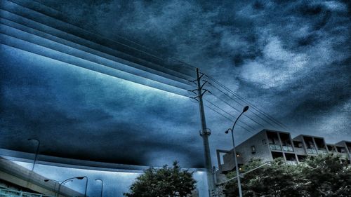 Low angle view of electricity pylon against cloudy sky