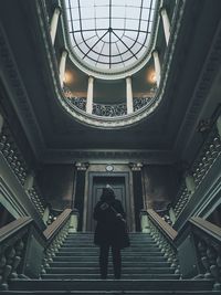 Low angle view of man standing on steps below skylight