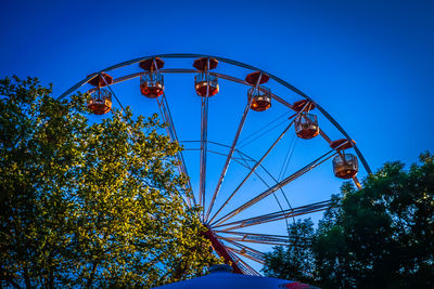 Low angle view of ferris wheel against clear blue sky