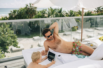 Midsection of shirtless man lying down in swimming pool