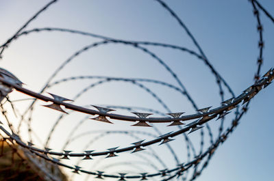 Low angle view of barbed wire against sky