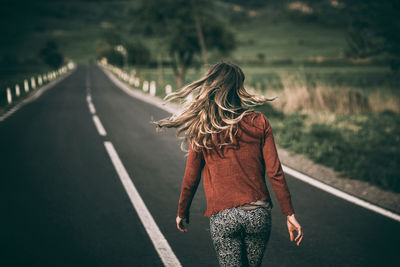 Rear view of woman walking on road