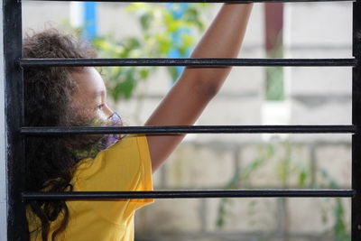 Side view of woman standing by railing against window